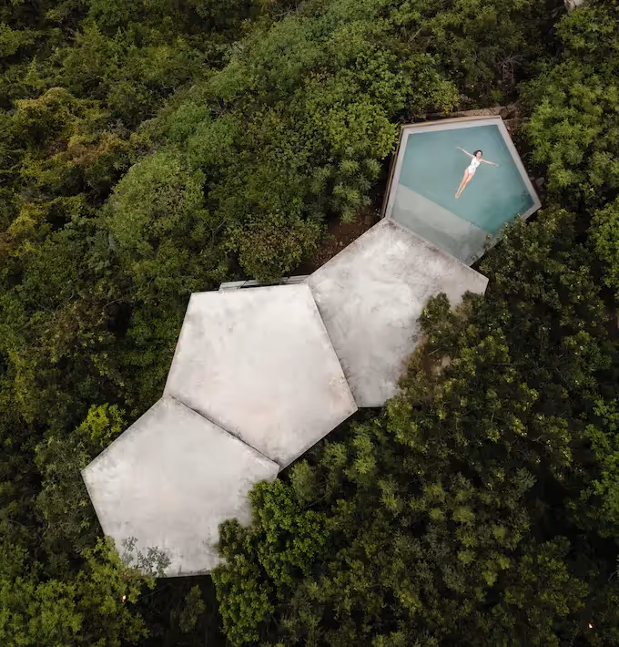 Aerial view of the white geometric architecture and pool at La Valise Mazunte Hotel restaurant, surrounded by dense jungle.