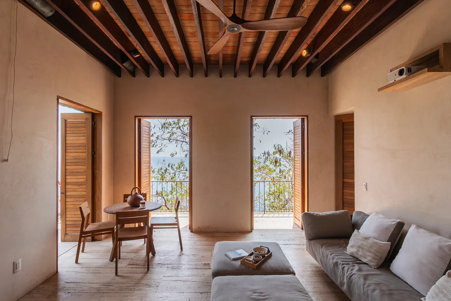Sala de estar de Master Suite Chicatana con sofá, mesa de comedor y altas puertas hacia el mar — La Valise Mazunte