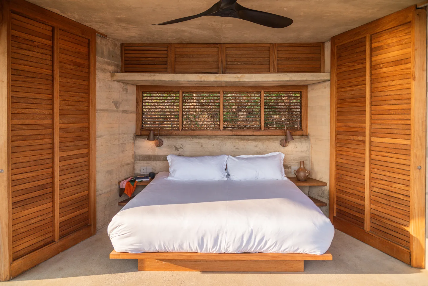Cama king enmarcada por persianas plegables de madera en Villa Pentágonos — La Valise Mazunte