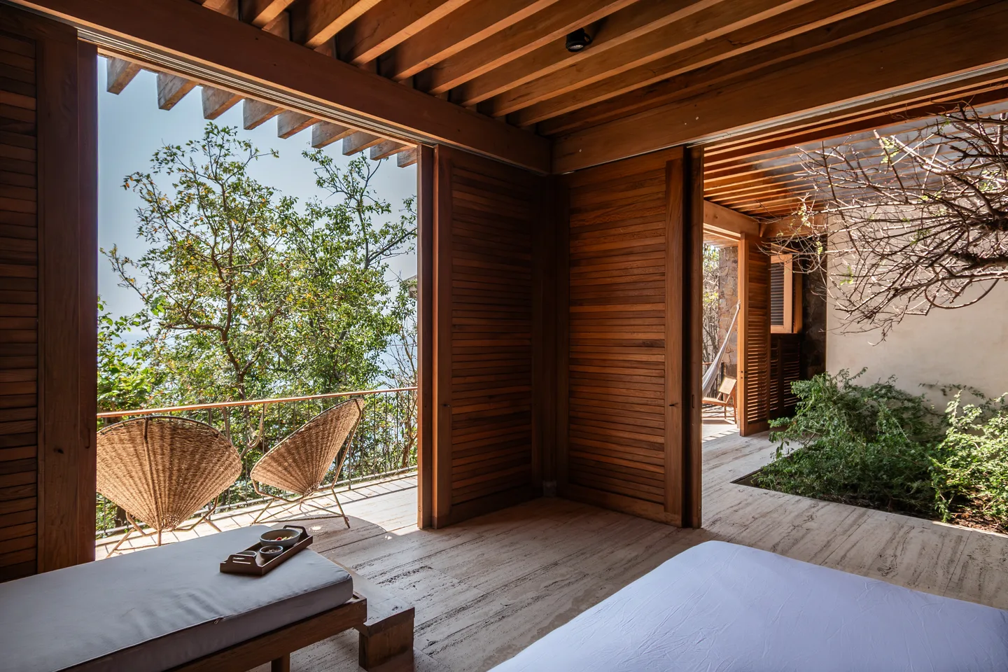 Wooden doors of Suite El Árbol opening to a planted terrace and tree canopy — La Valise Mazunte