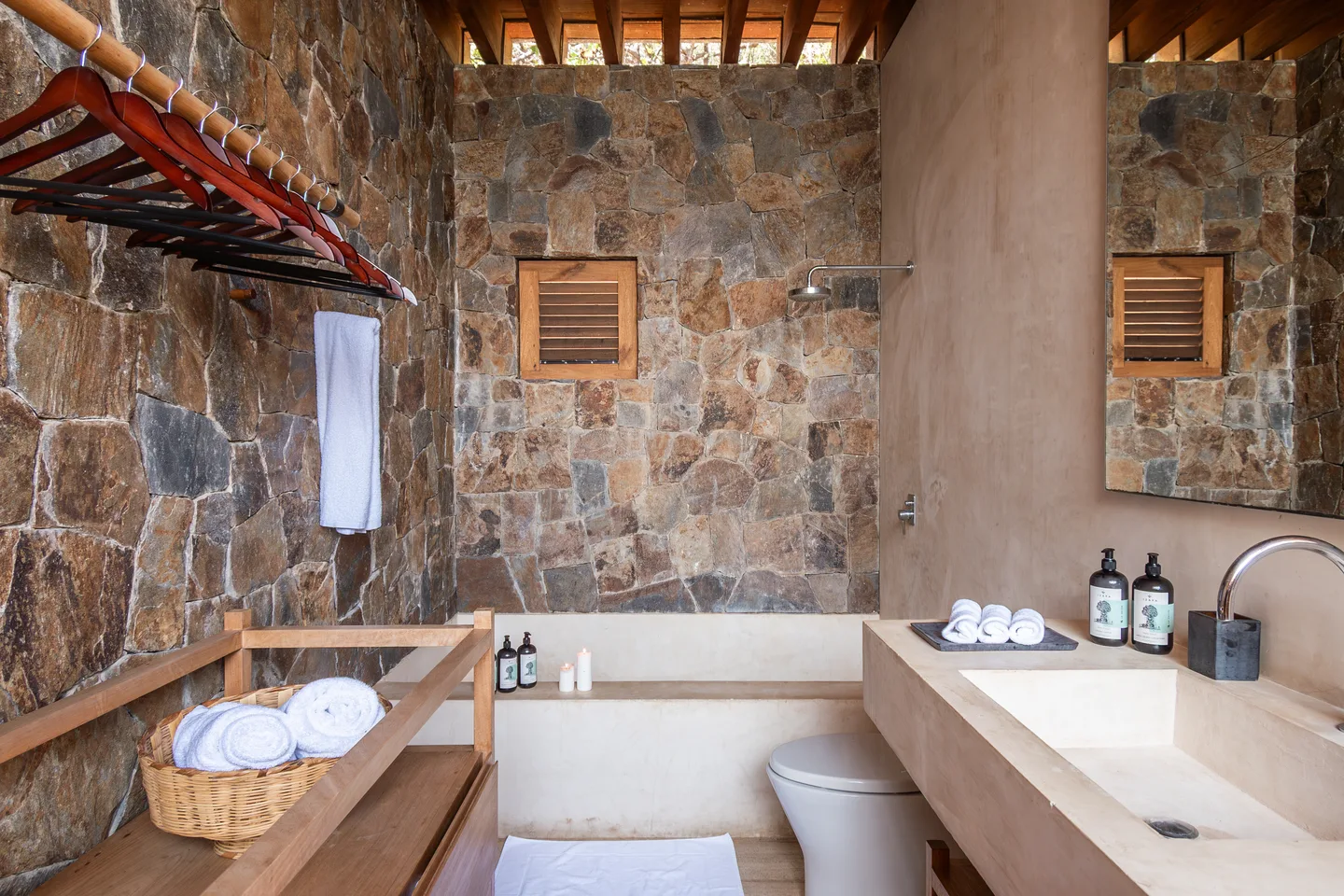 Baño con muros de piedra de la Suite El Árbol con tina y lavabos dobles — La Valise Mazunte