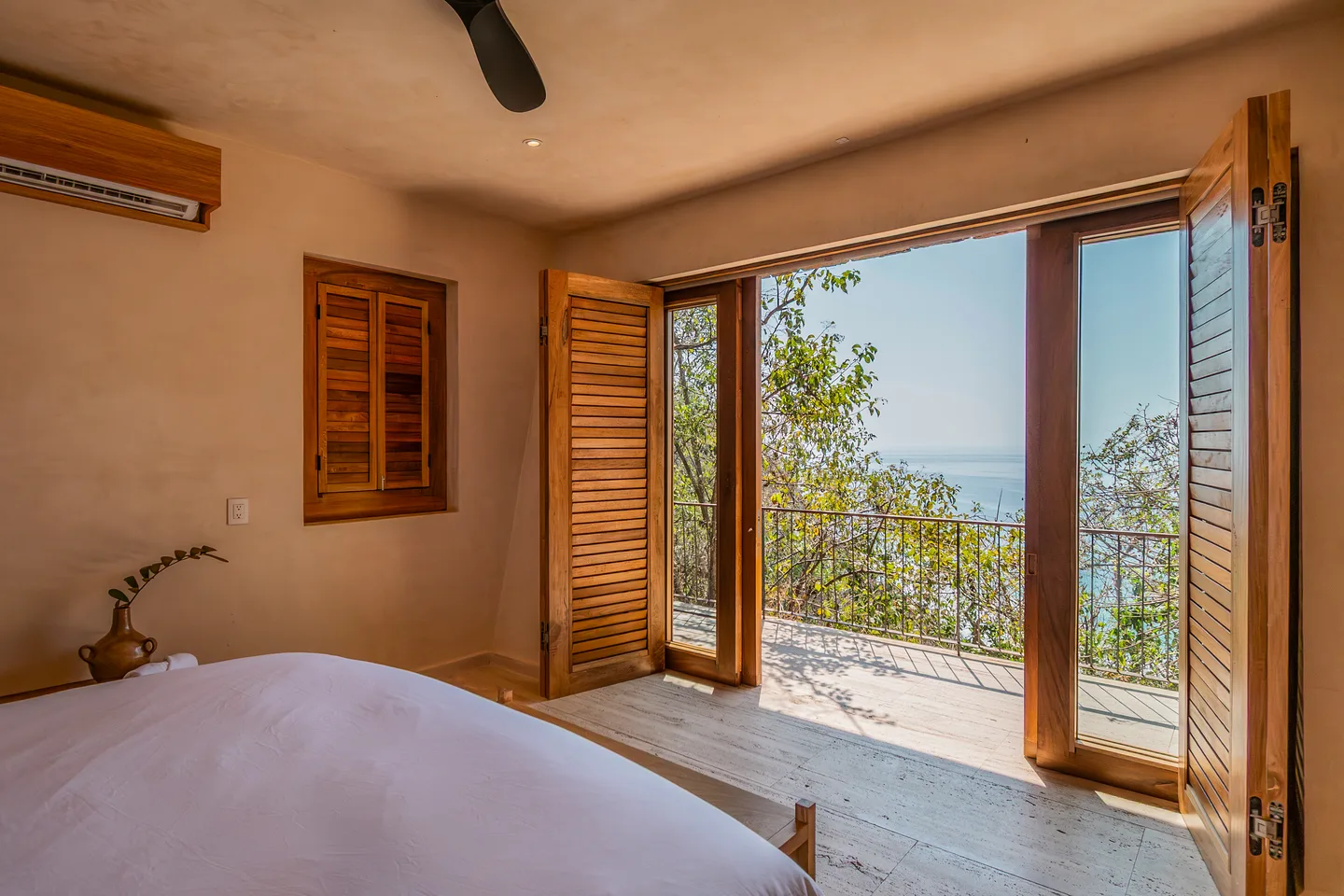 Bed in Suite Chukum facing glass doors with an ocean view — La Valise Mazunte