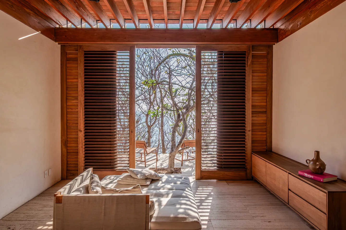 Sunken lounge of Suite Guayacán facing louvred doors and the trees — La Valise Mazunte