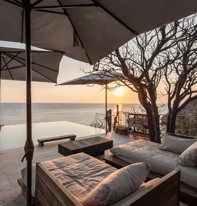 Sunset lounge terrace with umbrellas and bare trees at La Valise Mazunte