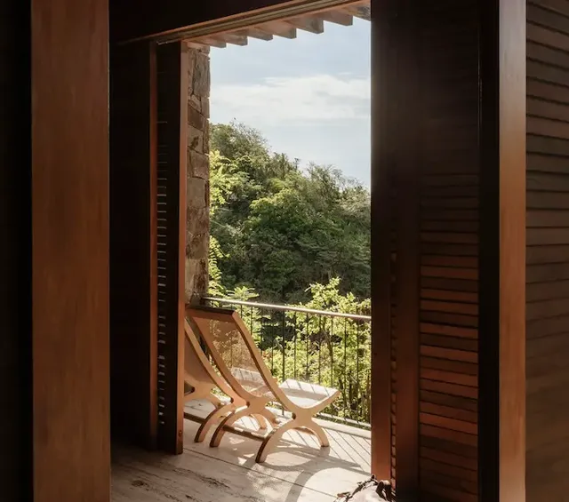 Wooden doors opening to a terrace with loungers and hillside views at La Valise Mazunte