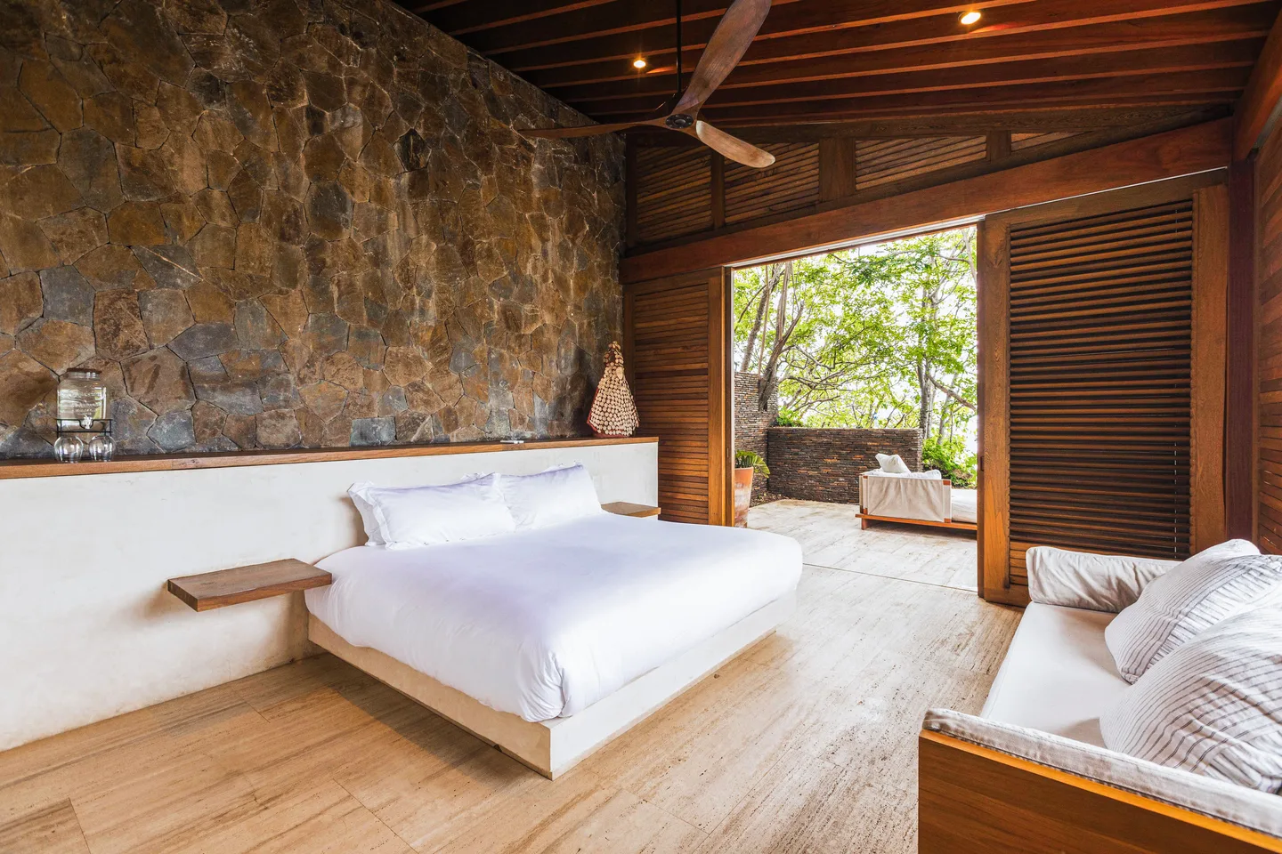 King bed beneath a stone wall in Suite Mar Azul with doors open to the terrace — La Valise Mazunte