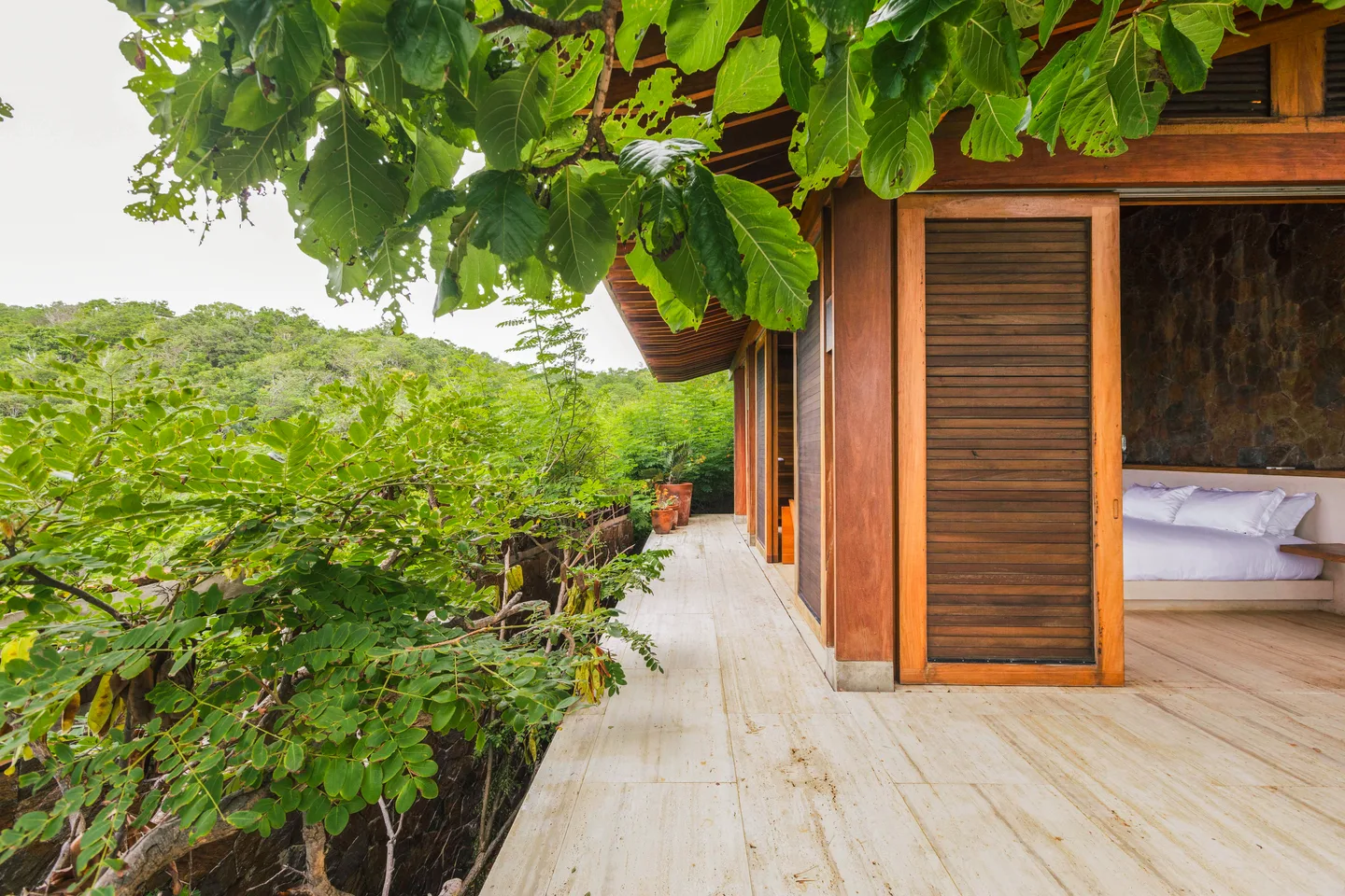 Deck y fachada de celosías de la Suite Mar Azul bajo los árboles — La Valise Mazunte